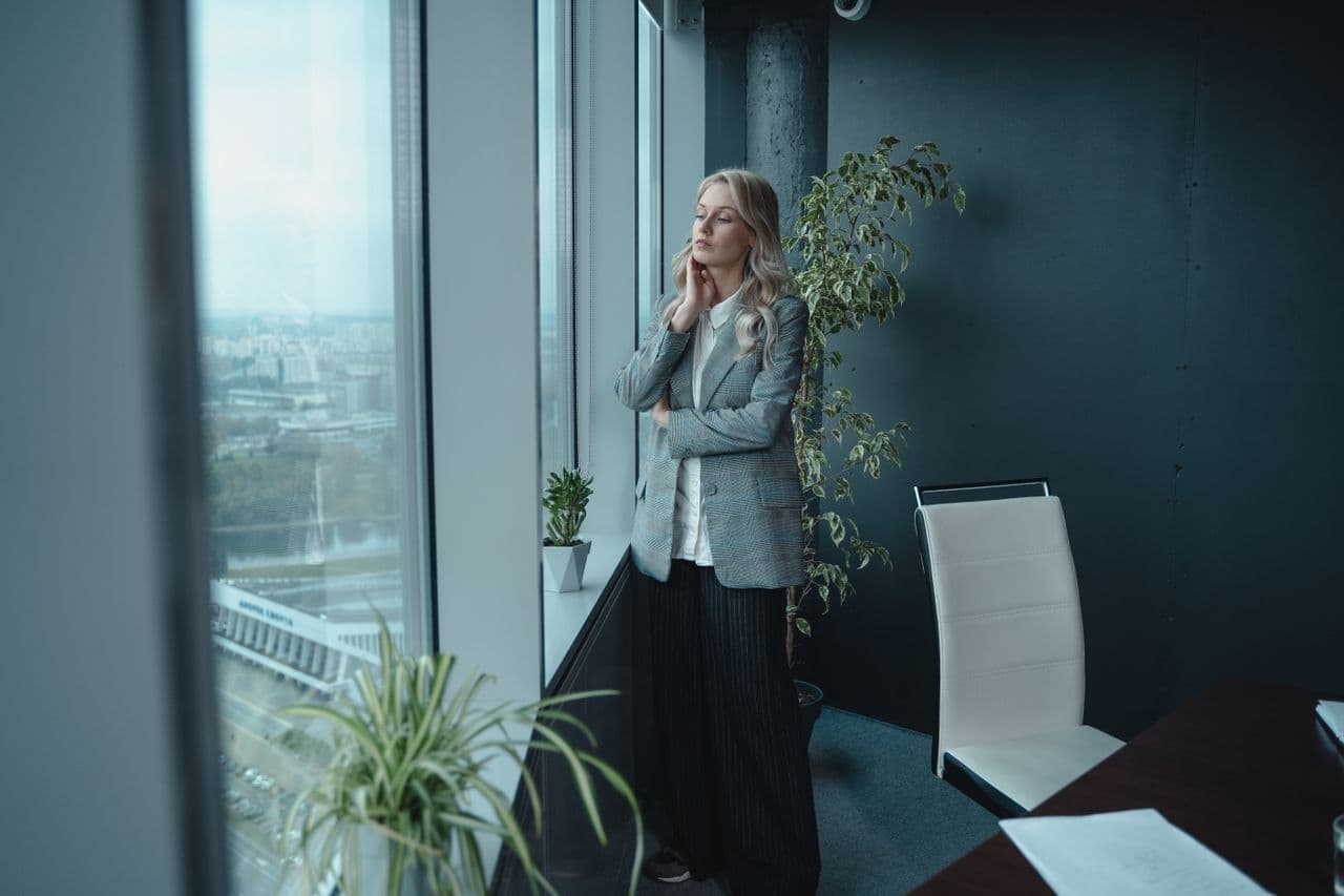 Businesswoman standing in an office, looking out of the window