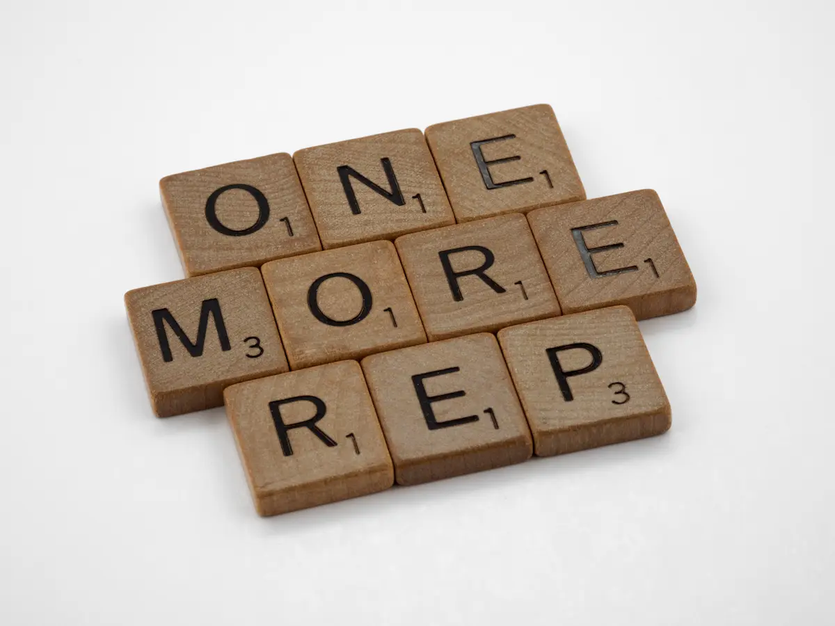 Scrabble tiles spelling out one more rep, a reminder that small gains build your one-rep max over time